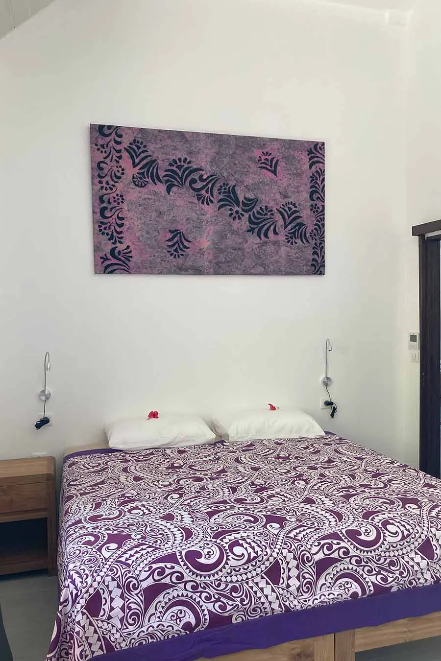 Double bed with artwork on the wall and lights in our vacation home in Bora Bora