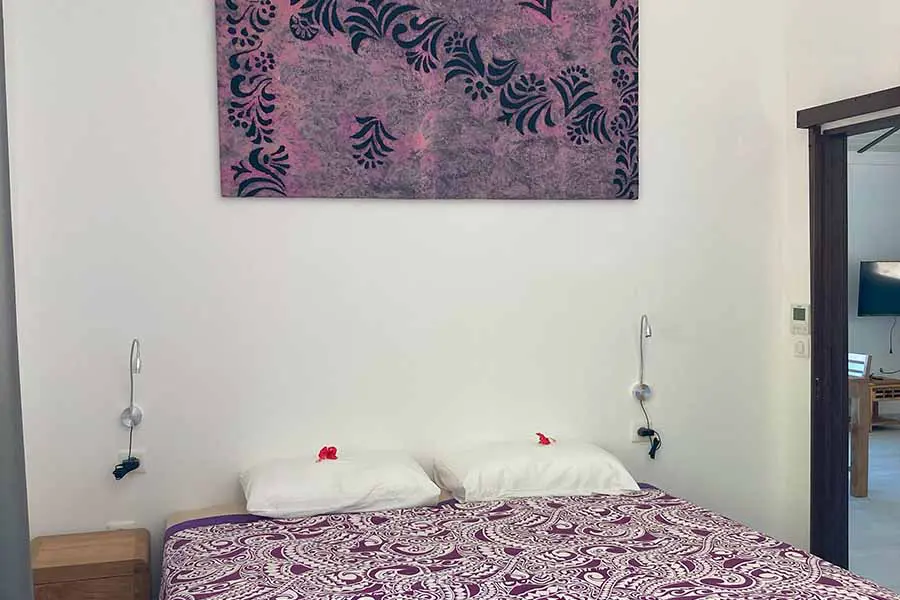 Double bed with artwork on the wall and lights in our vacation home in Bora Bora
