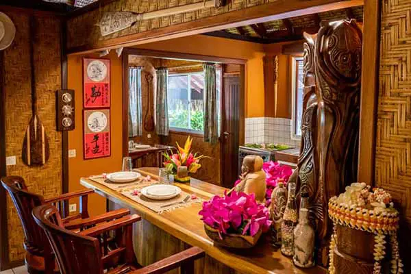 Bar en bois orné de sculptures tahitiennes à côté de la cuisine dans la maison de vacances à Bora Bora