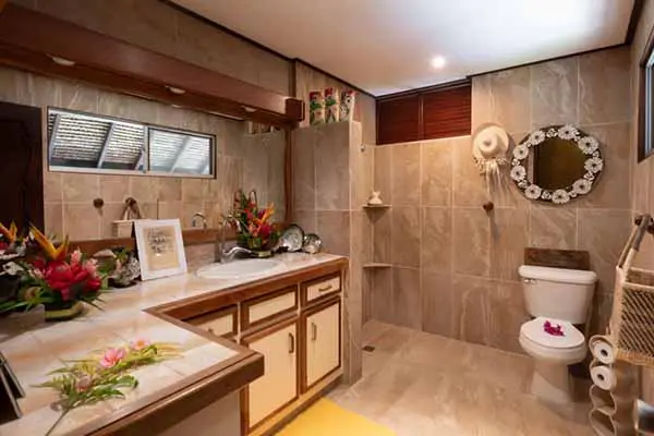 Salle de bains avec un lavabo et des toilettes décorées de fleurs tropicales dans la maison de vacances à Bora Bora