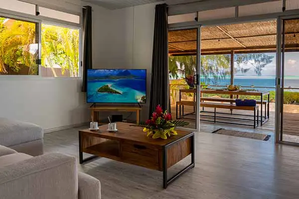 Salon avec baie vitrée donnant sur la terrasse en bord de mer dans notre maison de vacances à Bora Bora