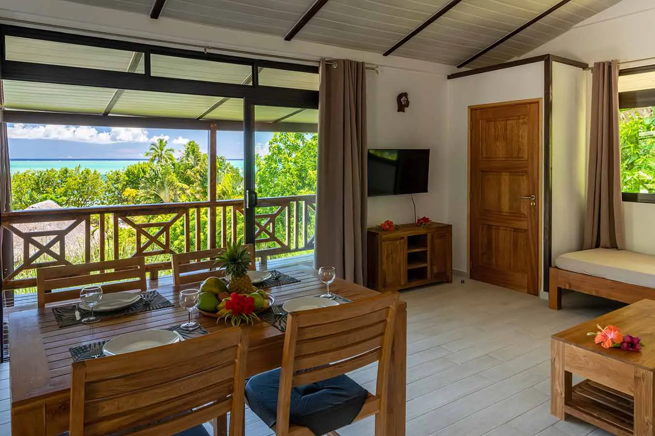 Dining table with living room and bay window overlooking the terrace with a view of the lagoon in our Bora Bora vacation home