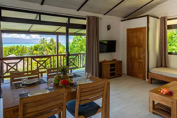 Table à manger avec salon et baie vitrée donnant sur terrasse avec vue sur le lagon dans notre maison de vacances à Bora Bora