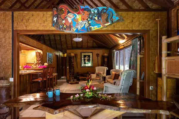 Salon polynésien avec canapé vintage et sculptures dans la maison de vacances à Bora Bora